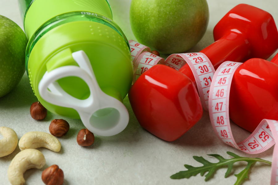 Weight loss accessories on white textured background, close up
